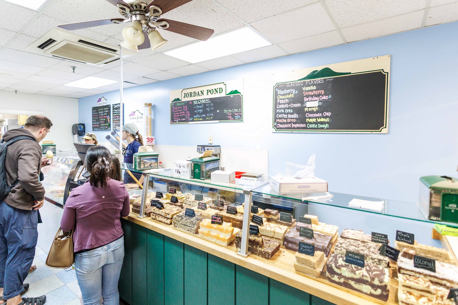Customers ordering at the wooden counter under the classic-flavors chalkboard.