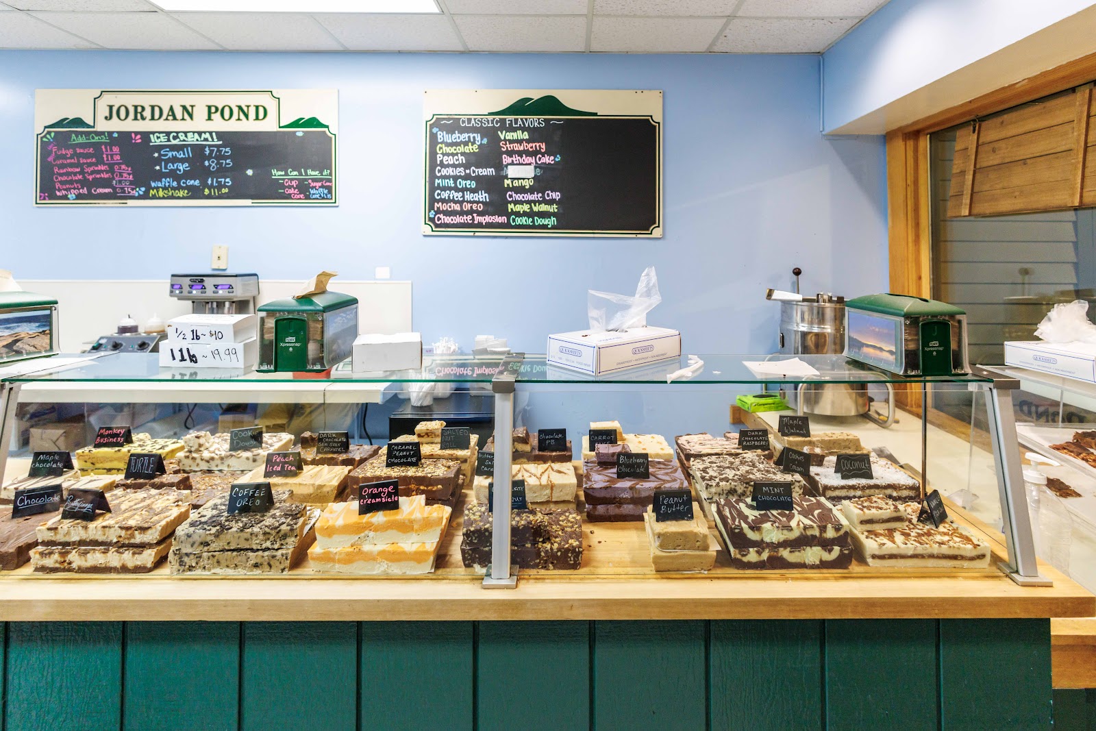 Rows of labeled fudge in the case below the chalkboard flavor menus on the pale-blue wall.